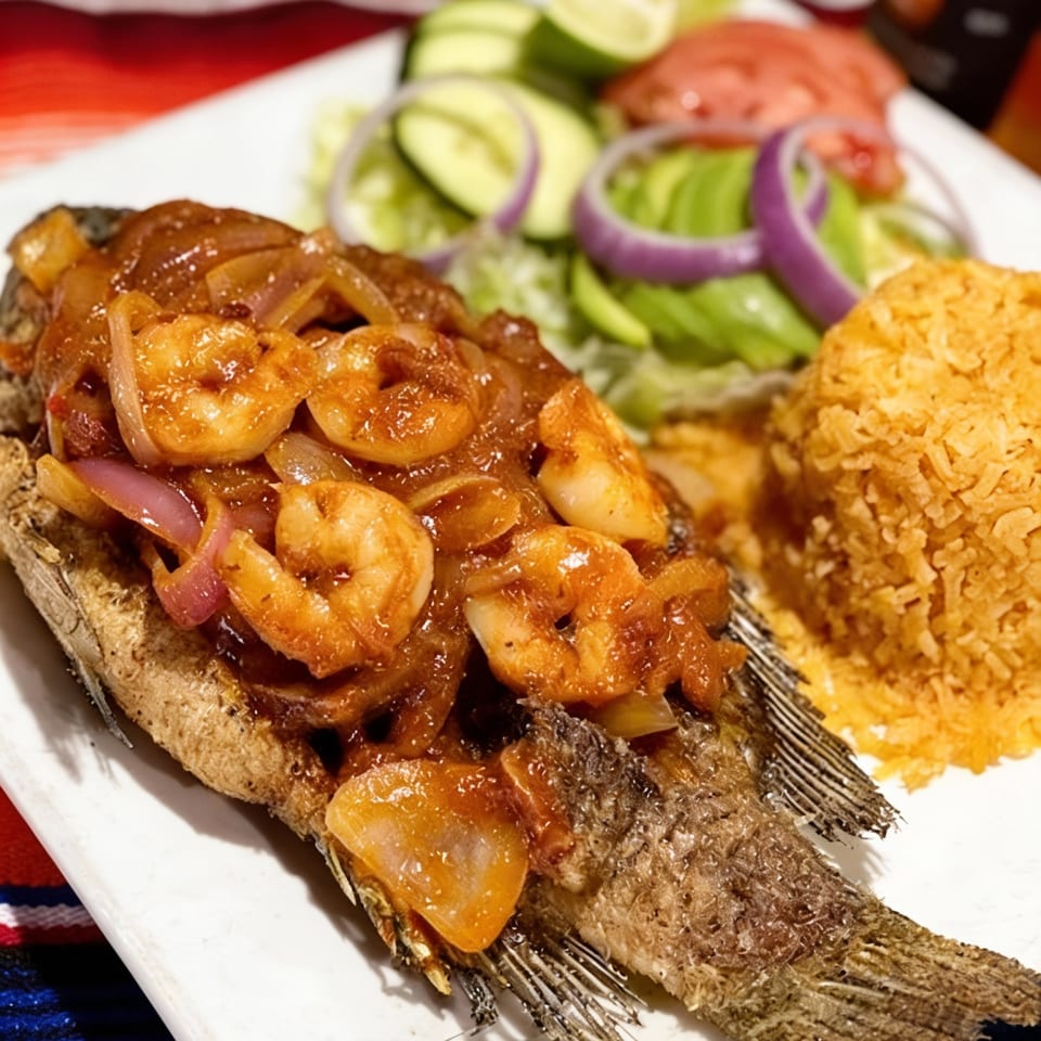 Fried whole fish topped with shrimp and onions, served with rice and a side salad.